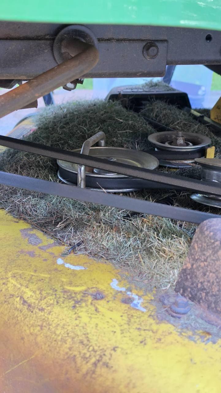 Riding mower deck belt and pulleys surrounded by grass clippings