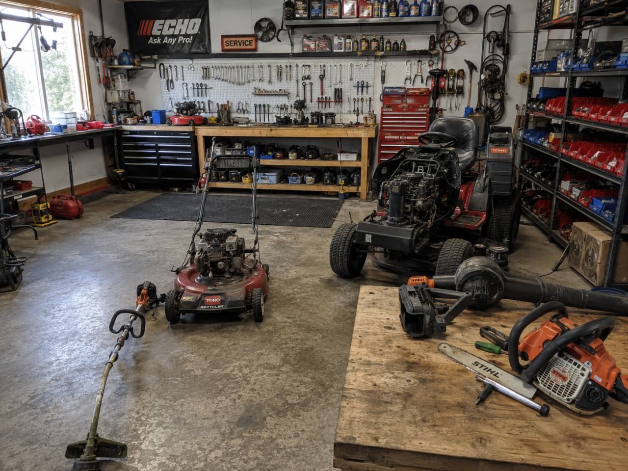 Small engine repair shop interior with a string trimmer and other equipment